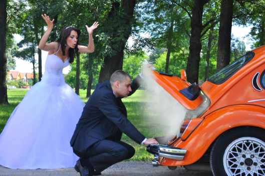woman in white wedding gown near orange car