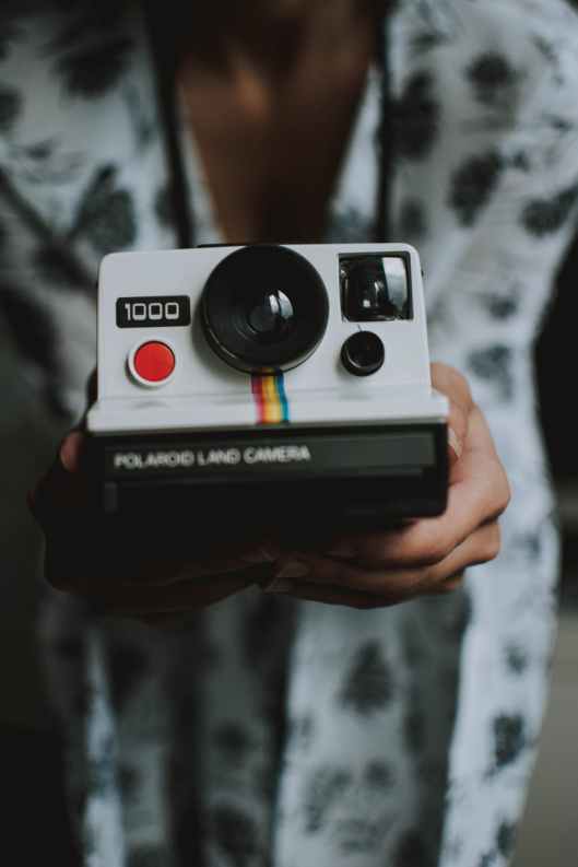 person holding white polaroid land camera