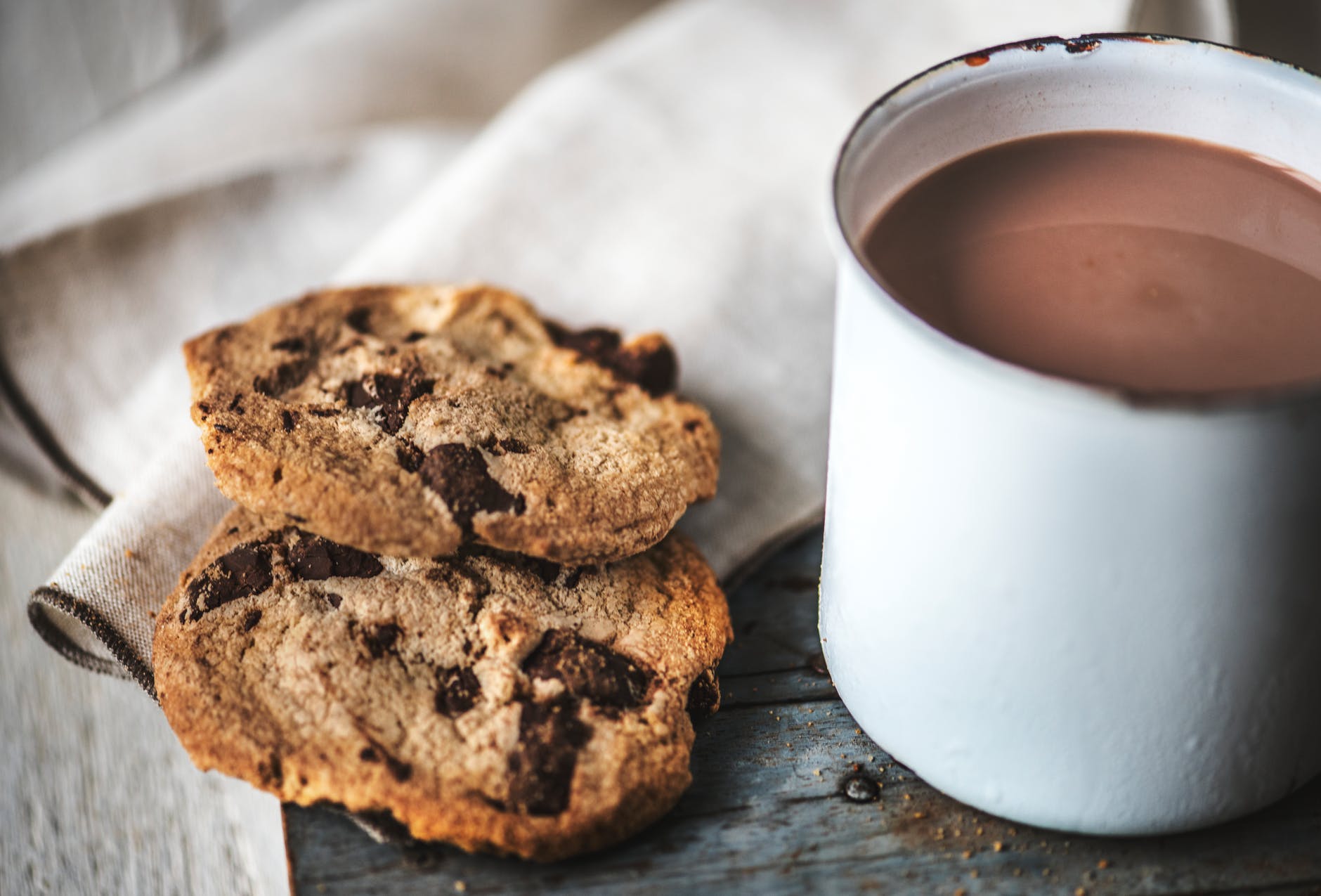 two cookies beside white metal mug
