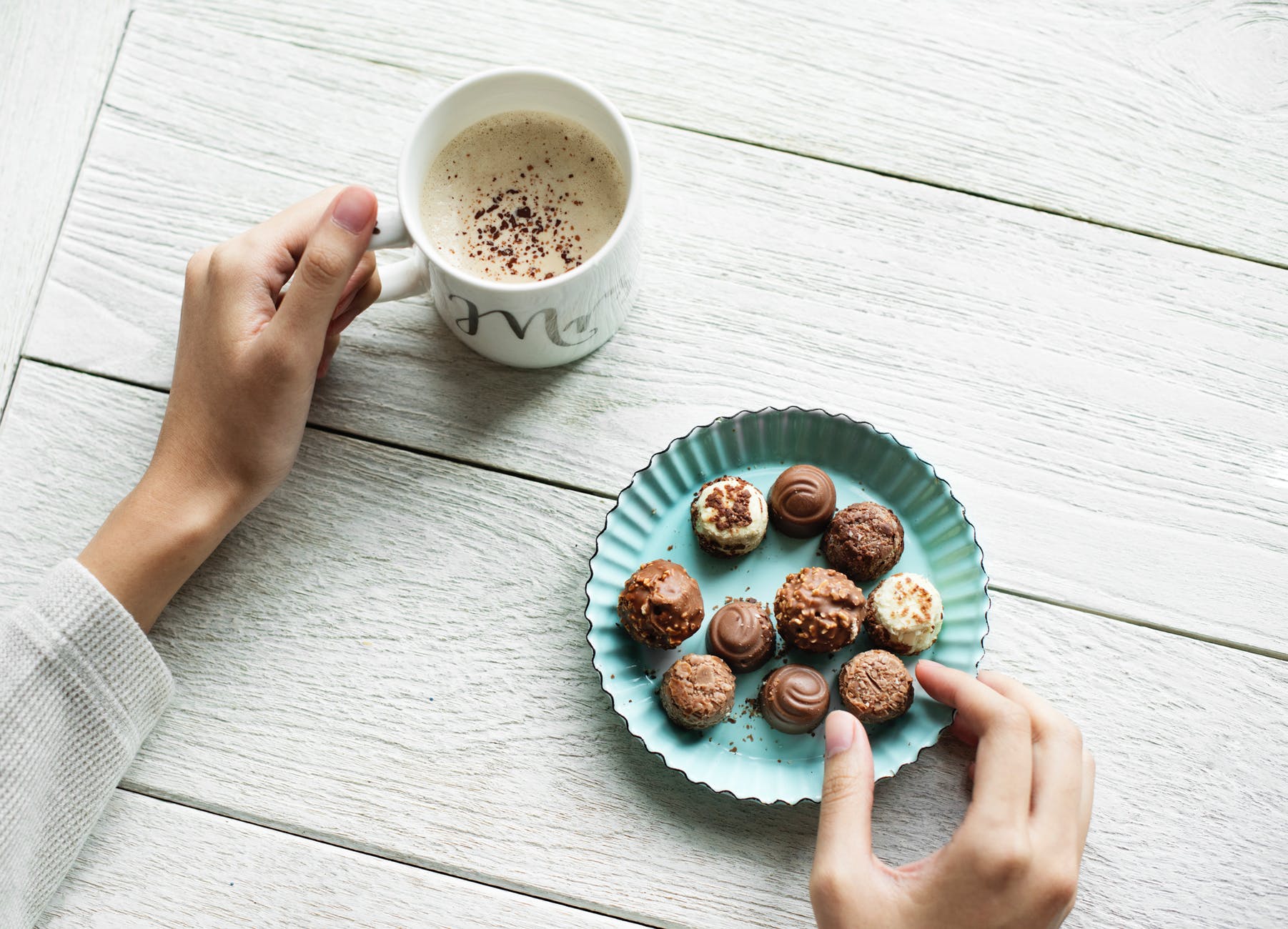 person holding chocolates and white ceramic mug