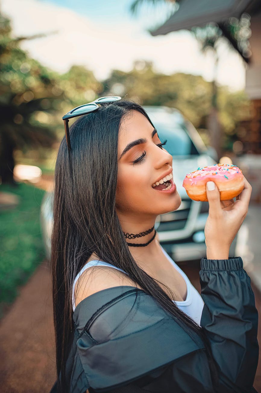 woman wearing black jacket holding doughnut