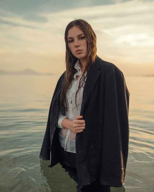 woman in black coat standing on beach